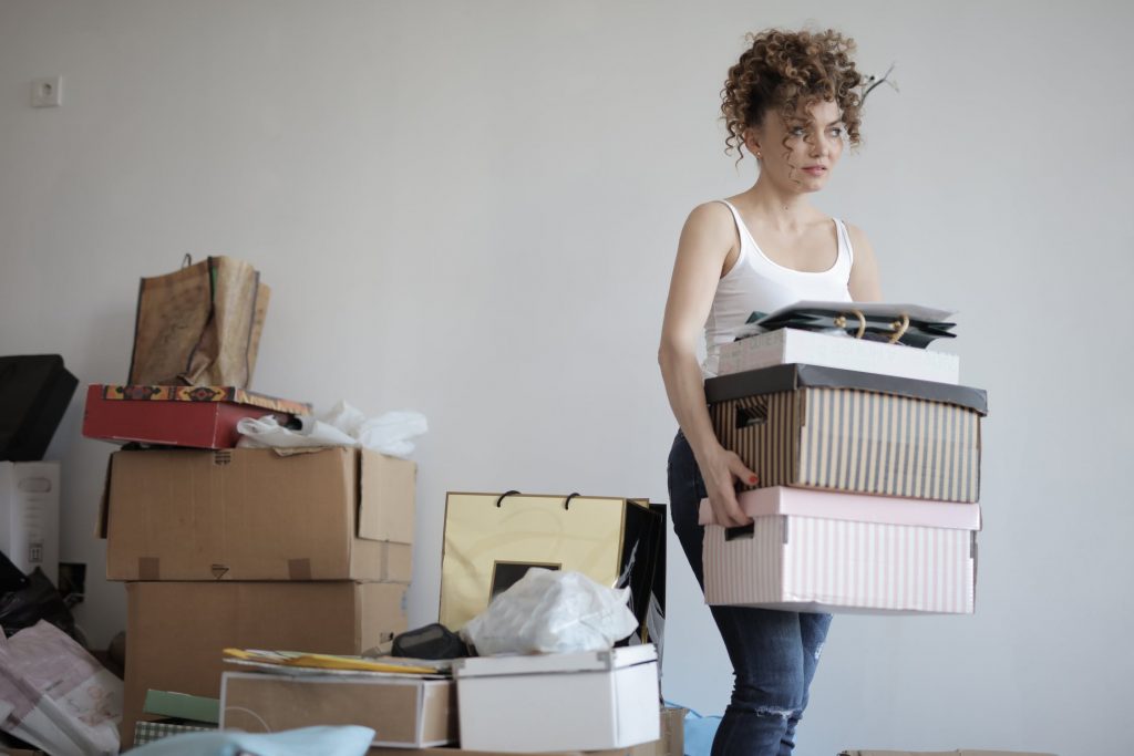 Woman holding boxes with a pile of things behind her